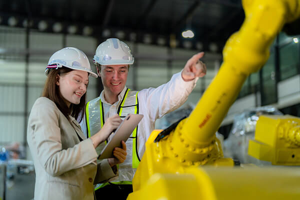 Factory engineers inspecting machinery with a tablet
